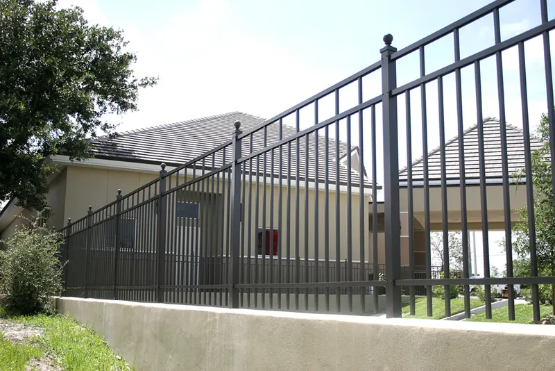 Bronze aluminum fence on a low concrete wall in a residential yard
