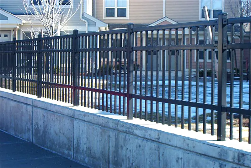 Black aluminum fence on top of a concrete retaining wall