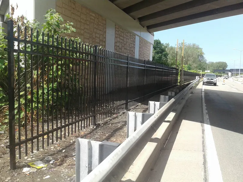 Black aluminum spear-top fence running along a roadway
