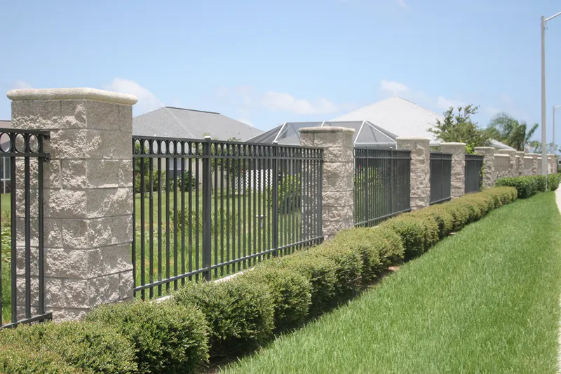 Black aluminum fence between stacked stone columns