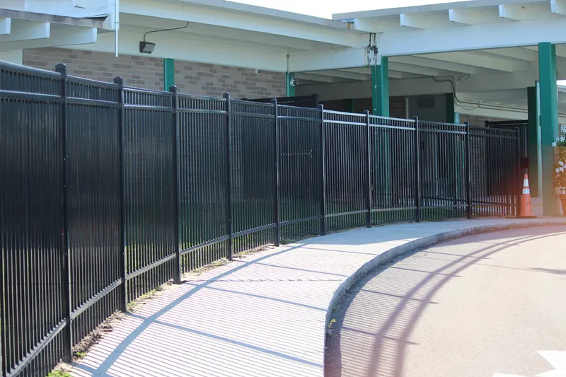 Black aluminum commercial fence curving along a walkway