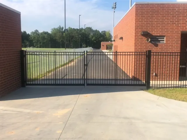 Black aluminum double-swing gate at a school athletic facility