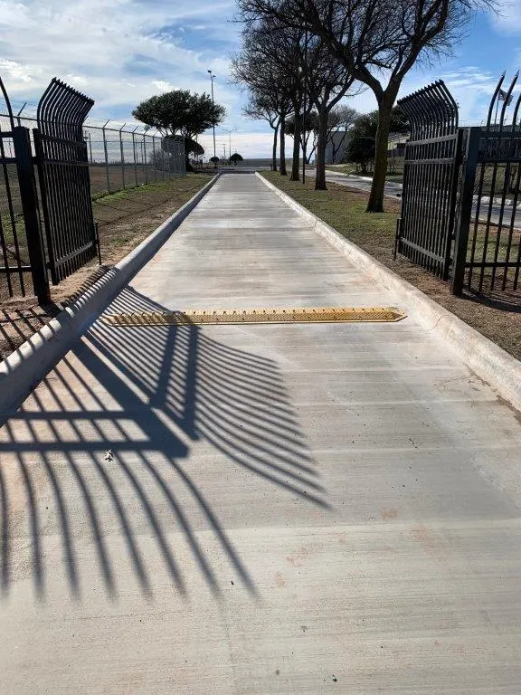 Two open black spear-top driveway gates on a concrete drive