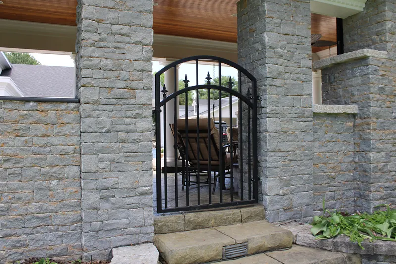 Arched black walk-through gate set between stone pillars