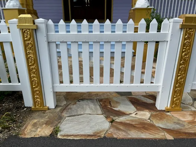 White vinyl picket fence with ornate gold decorative posts