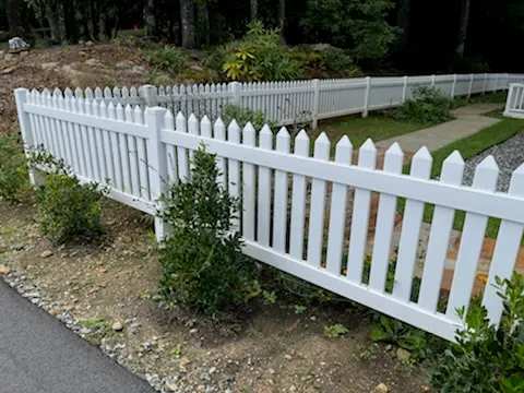 White vinyl picket fence along a residential driveway