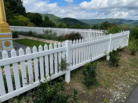 White vinyl picket fence with rolling mountains in the background