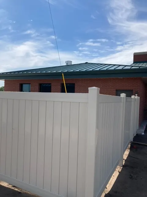 White vinyl privacy fence panels next to a red brick building